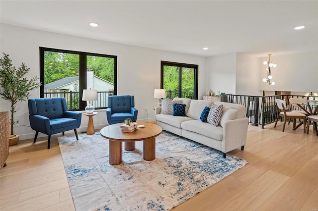 living area featuring light wood-style floors, recessed lighting, baseboards, and a notable chandelier