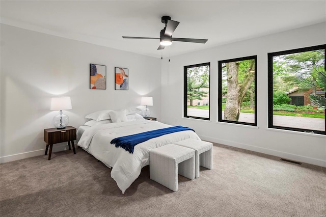 bedroom with baseboards, visible vents, light carpet, and ceiling fan