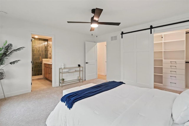 bedroom with visible vents, baseboards, a barn door, carpet flooring, and ensuite bath