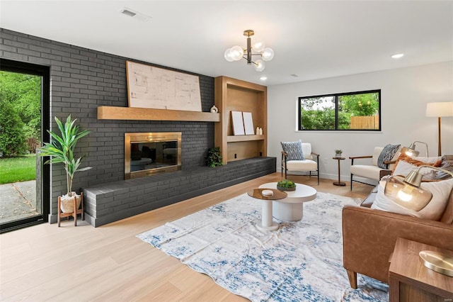 living room with plenty of natural light, a brick fireplace, wood finished floors, and visible vents