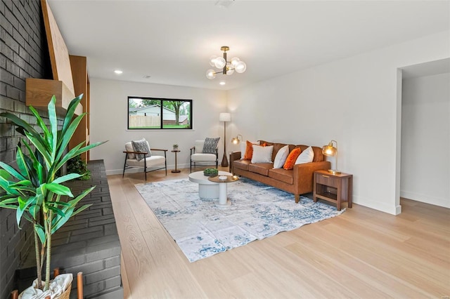 living area with recessed lighting, baseboards, an inviting chandelier, and light wood finished floors