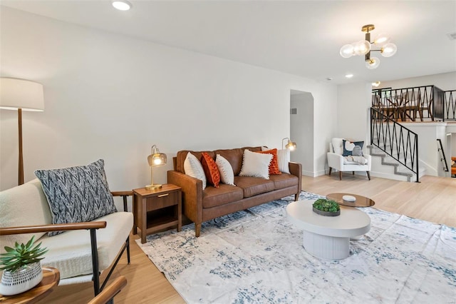 living area with stairs, wood finished floors, baseboards, recessed lighting, and a chandelier