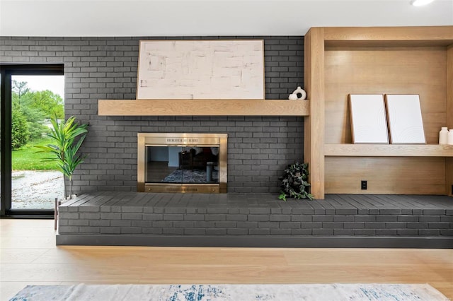 unfurnished living room with a brick fireplace and wood finished floors