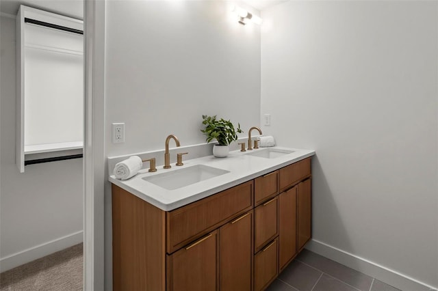 full bath featuring a sink, baseboards, tile patterned floors, and double vanity