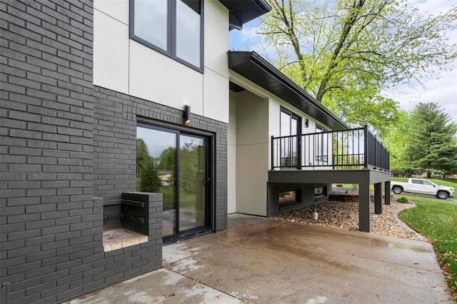 view of side of property with stucco siding, a deck, and brick siding