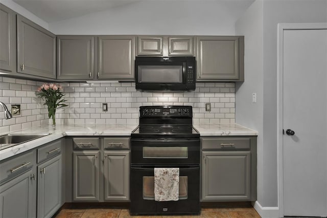 kitchen with a sink, gray cabinetry, decorative backsplash, vaulted ceiling, and black appliances