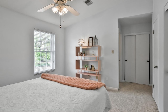 bedroom featuring ceiling fan, light carpet, baseboards, visible vents, and a closet