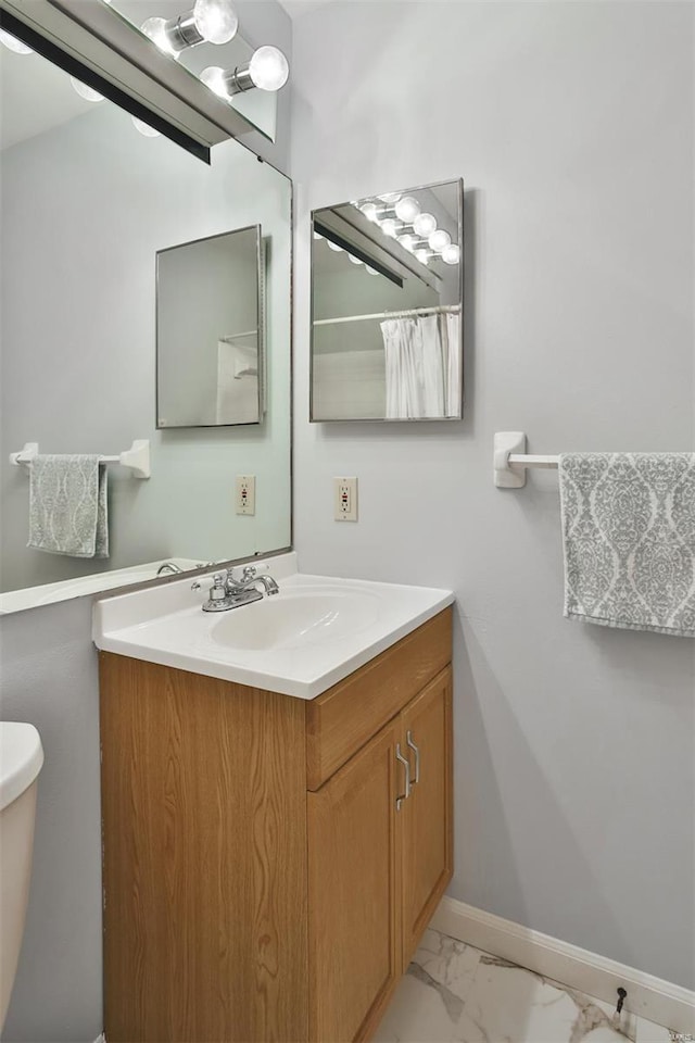 full bathroom featuring vanity, marble finish floor, baseboards, and toilet