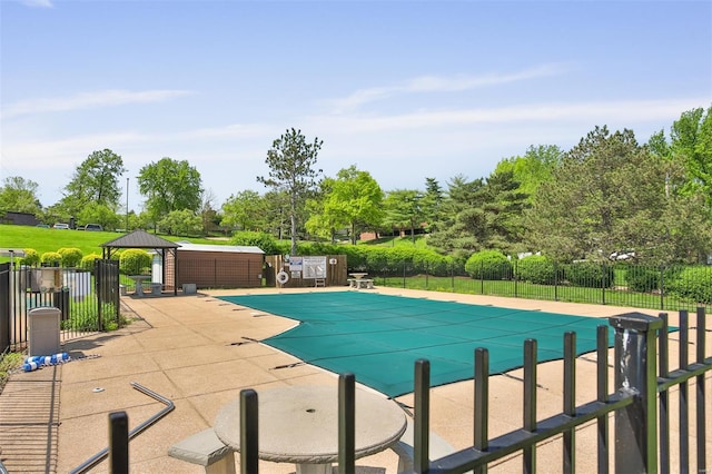 community pool with a gazebo, fence, and a patio area