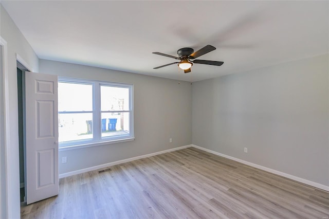 spare room featuring baseboards, ceiling fan, light wood-style floors, and visible vents