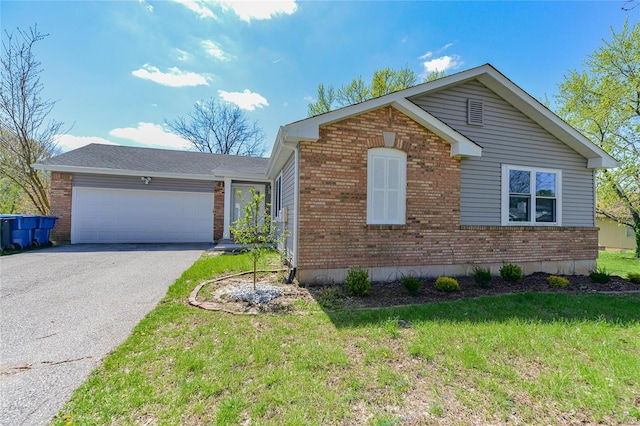 view of front facade featuring an attached garage, brick siding, a front yard, and aphalt driveway