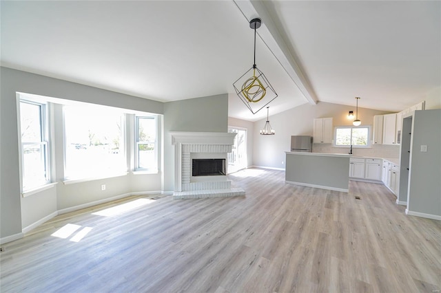 unfurnished living room featuring baseboards, light wood-type flooring, and vaulted ceiling with beams