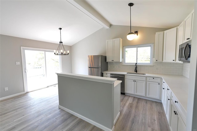 kitchen with plenty of natural light, a sink, light wood-style floors, tasteful backsplash, and appliances with stainless steel finishes