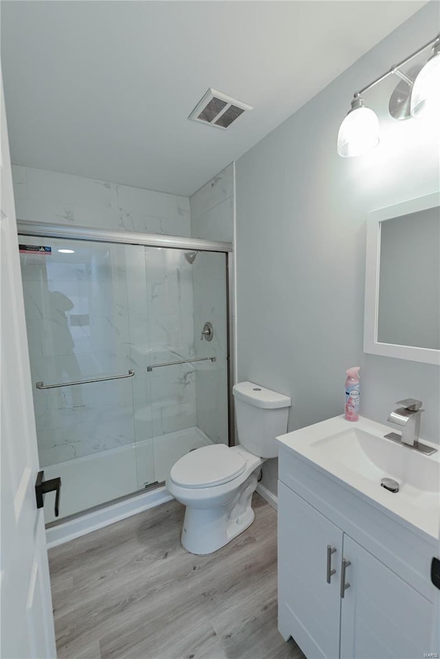 bathroom with toilet, visible vents, a stall shower, and wood finished floors