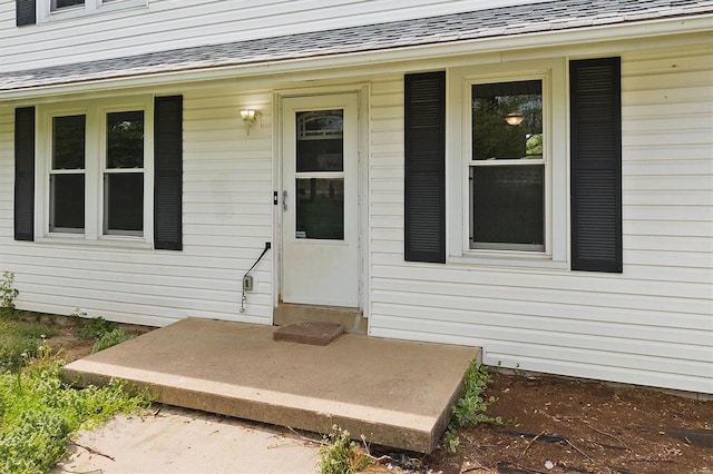 doorway to property with a porch and roof with shingles