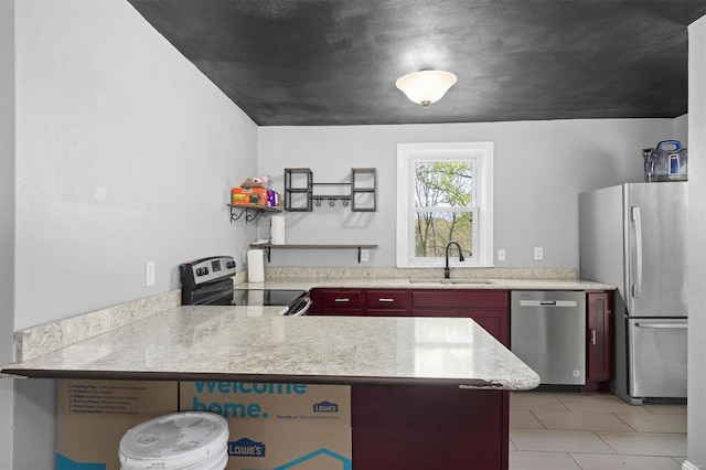 kitchen featuring reddish brown cabinets, light countertops, a sink, light tile patterned floors, and stainless steel appliances
