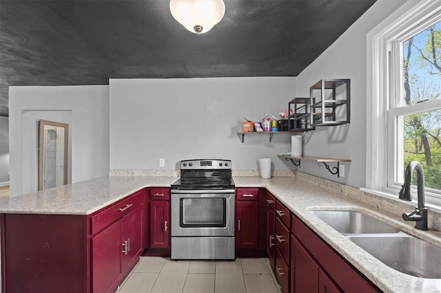 kitchen featuring red cabinetry, electric range, a peninsula, light countertops, and a sink
