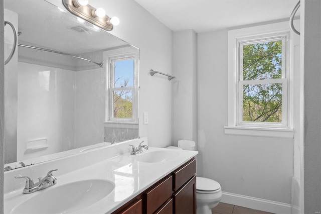 bathroom featuring toilet, tile patterned floors, walk in shower, and a sink