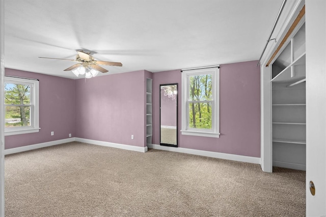 carpeted spare room featuring baseboards and ceiling fan