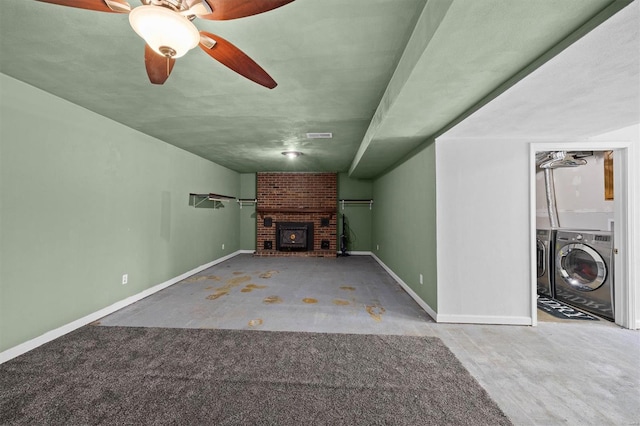 unfurnished living room featuring washing machine and clothes dryer, baseboards, a brick fireplace, and ceiling fan