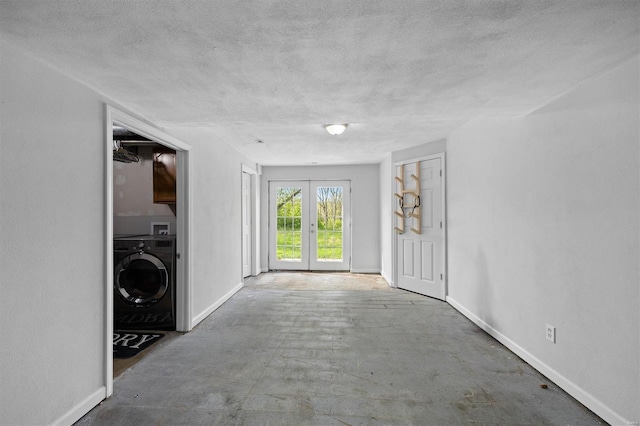 entryway with baseboards, a textured ceiling, washer / dryer, and unfinished concrete floors