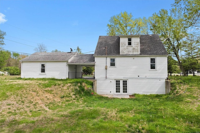rear view of house with french doors, a yard, and roof with shingles