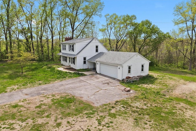 exterior space featuring an attached garage, a front lawn, aphalt driveway, and a chimney