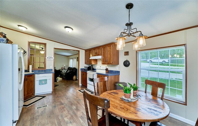 dining area with visible vents, crown molding, vaulted ceiling, wood finished floors, and a chandelier