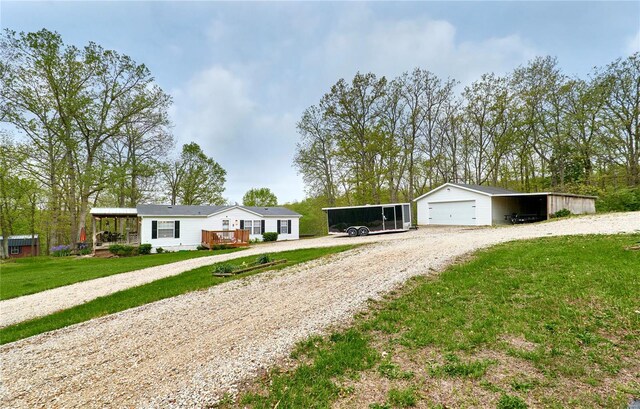 view of front of property with an outdoor structure, a front yard, gravel driveway, and a detached garage