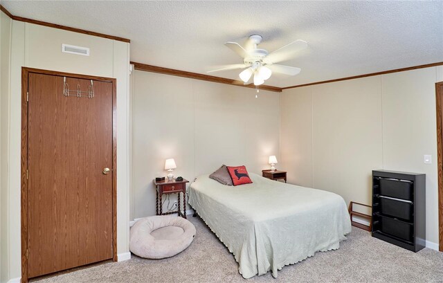 carpeted bedroom featuring visible vents, ornamental molding, a textured ceiling, and ceiling fan
