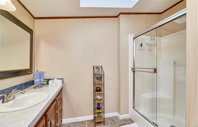 bathroom with a skylight, vanity, ornamental molding, and a stall shower