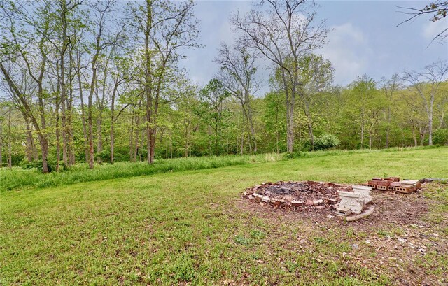 view of yard with a wooded view and an outdoor fire pit