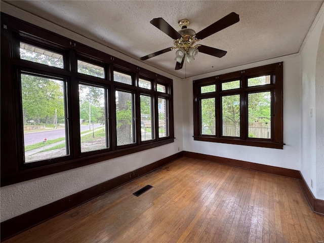 spare room with baseboards, a wealth of natural light, a textured ceiling, and visible vents