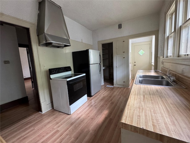 kitchen with wall chimney range hood, a sink, range with electric stovetop, and light wood-style floors