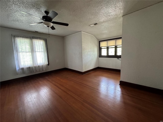 empty room with visible vents, a textured ceiling, ceiling fan, and dark wood-style floors