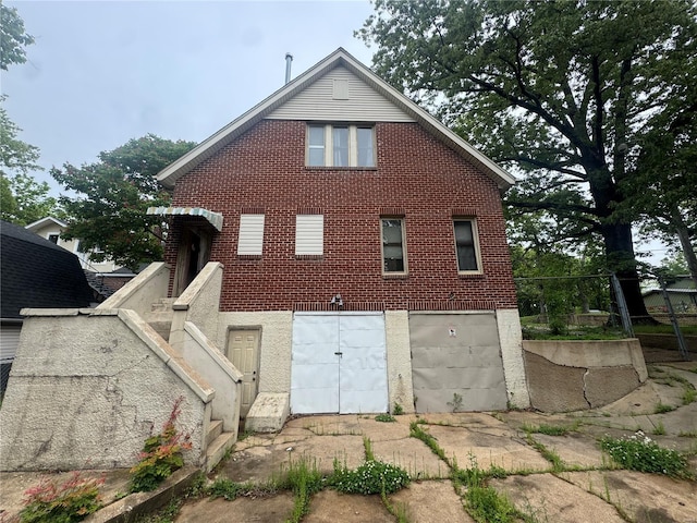 rear view of property featuring brick siding and a garage