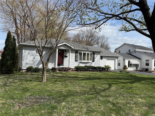 view of front of house with roof with shingles, an attached garage, driveway, and a front yard