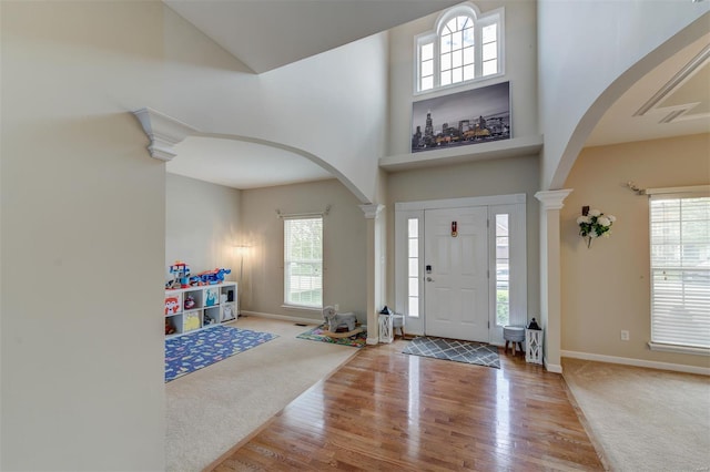entrance foyer featuring wood finished floors, arched walkways, a wealth of natural light, and a towering ceiling