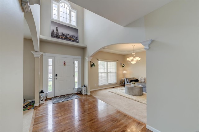 foyer featuring an inviting chandelier, wood finished floors, baseboards, a high ceiling, and arched walkways