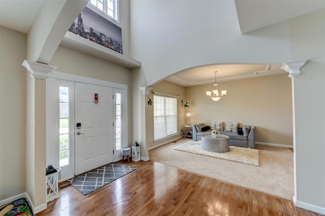 foyer with arched walkways, baseboards, ornate columns, and wood finished floors