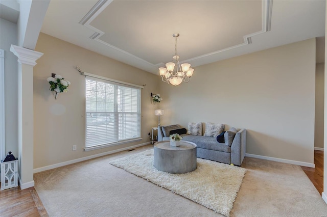 carpeted living area featuring baseboards, a notable chandelier, and a raised ceiling