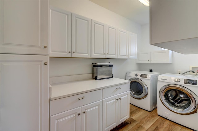 clothes washing area featuring separate washer and dryer, cabinet space, and light wood-style floors
