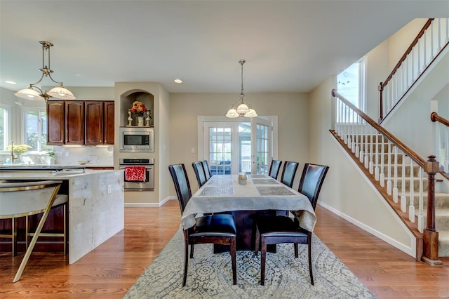 dining room featuring light wood-style floors, baseboards, and stairs