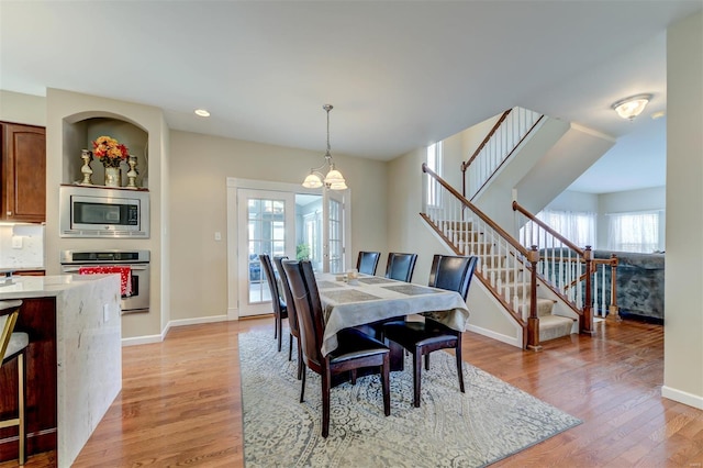 dining room with light wood finished floors, a chandelier, recessed lighting, baseboards, and stairway
