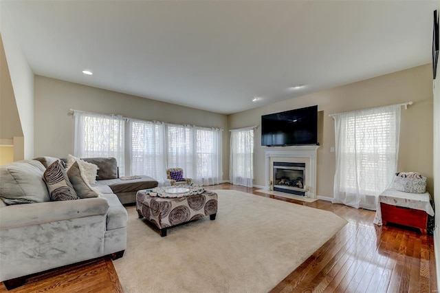 living area featuring recessed lighting, baseboards, a fireplace with flush hearth, and wood finished floors