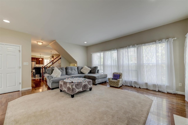 living room featuring wood finished floors, stairway, baseboards, a chandelier, and recessed lighting