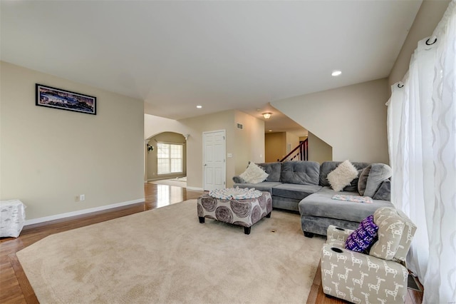 living room with arched walkways, recessed lighting, baseboards, wood finished floors, and stairway