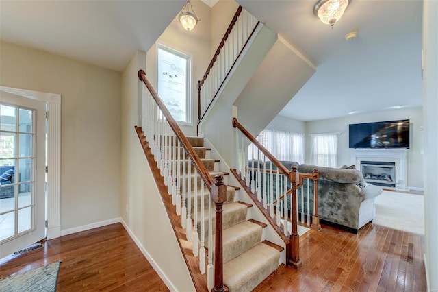 staircase with baseboards, visible vents, wood finished floors, and a fireplace