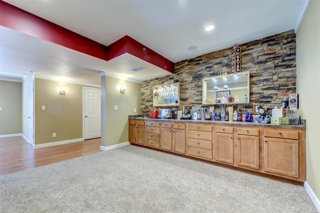 bar with visible vents, ornamental molding, baseboards, light colored carpet, and light wood finished floors