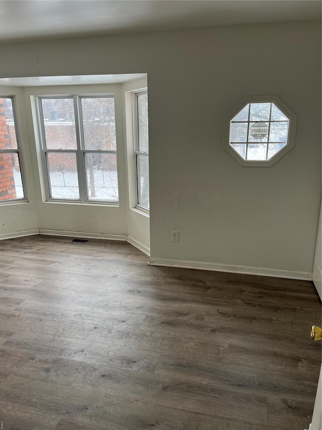 empty room with baseboards, dark wood-style floors, and plenty of natural light
